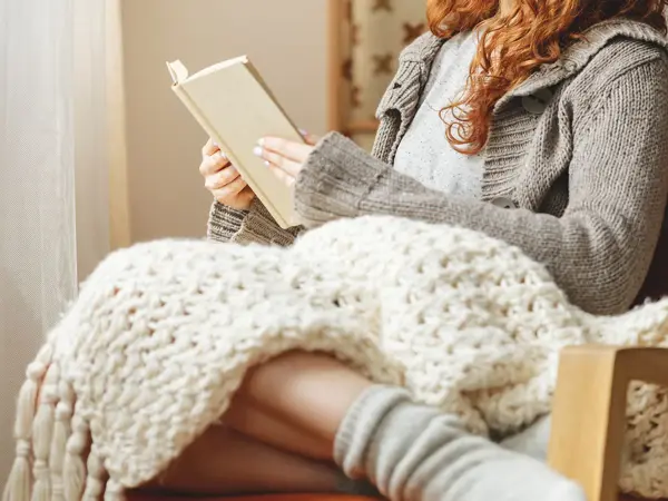 Happy young woman reading a book in a chair