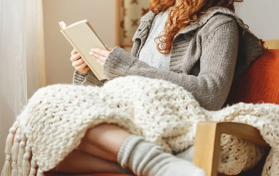 Happy young woman reading a book in a chair
