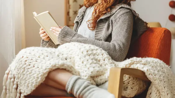 Happy young woman reading a book in a chair