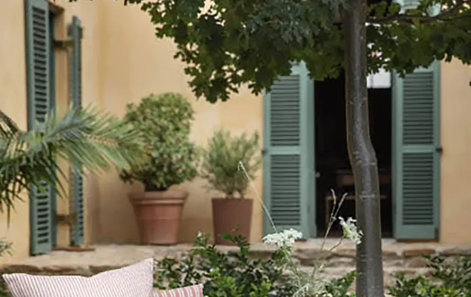 Rotting stol med krakk med rosa puter i en bakgård med mange grønne planter