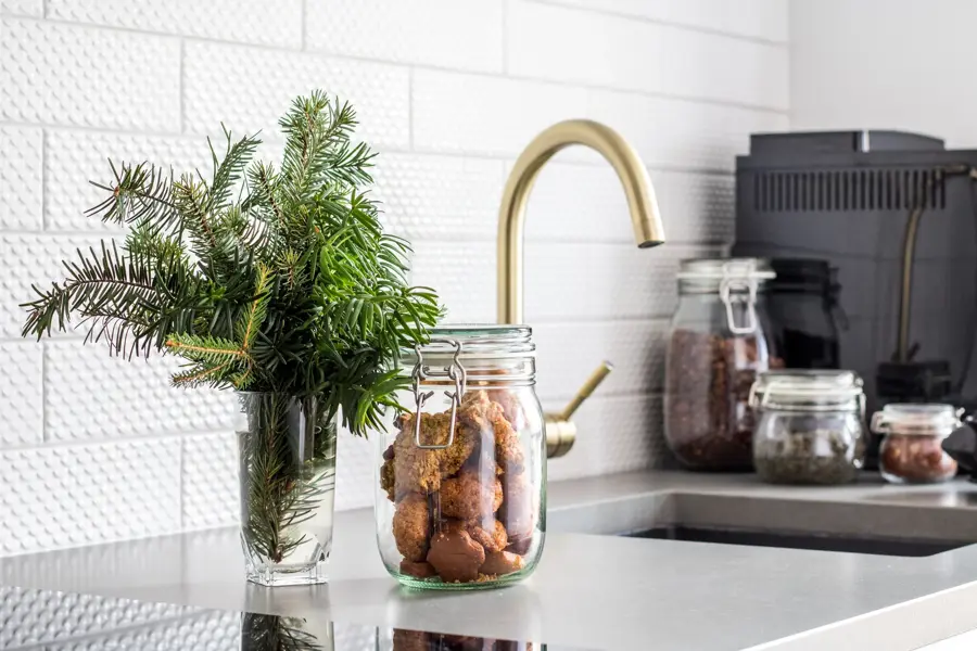 Krukker med mat i og glass med urter foran kjøkken med gullvask