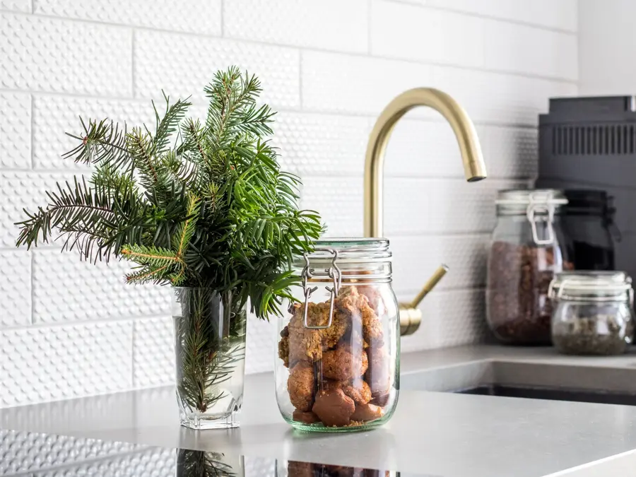 Krukker med mat i og glass med urter foran kjøkken med gullvask