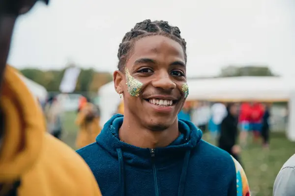En smilende ung mann med glitter i ansiktet