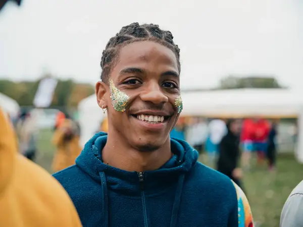 En smilende ung mann med glitter i ansiktet