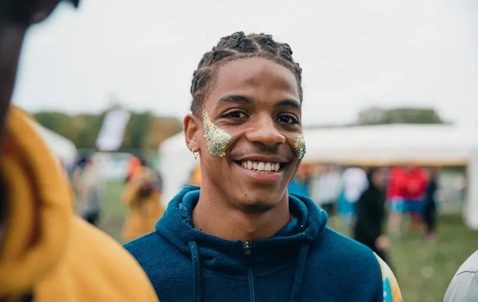 En smilende ung mann med glitter i ansiktet