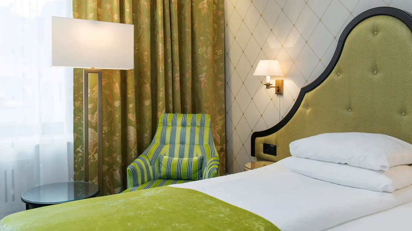 Stor seng med stol på Standard singelrom på Hotel Bristol i Oslo sentrum