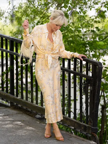 Dame i gul blomstrete kjole og bluse og sandaler