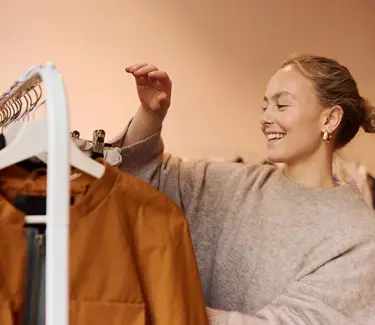 Dame sorterer klær på et stativ i en bruktubutikk