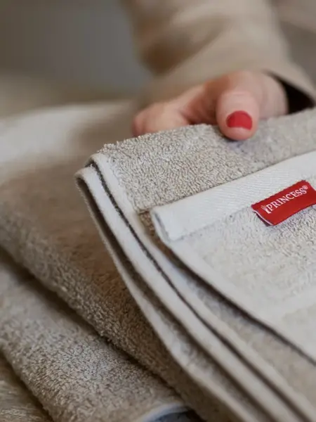 Hånd holder håndduk med Princessmerke på
