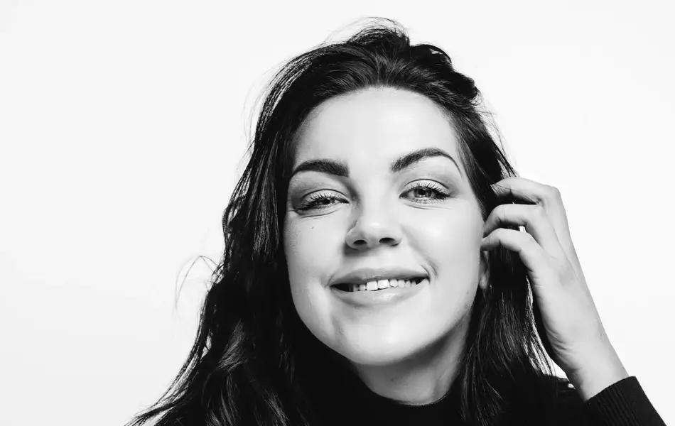 Ung kvinne med mørkt hår som smiler og har utsagnet Slutt aldri å drømme, fordi det er drømmene i livet som gir oss noe å lengte etter. 