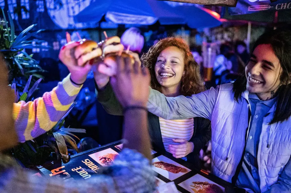 Friends toasting with hamburguers outdoors at night