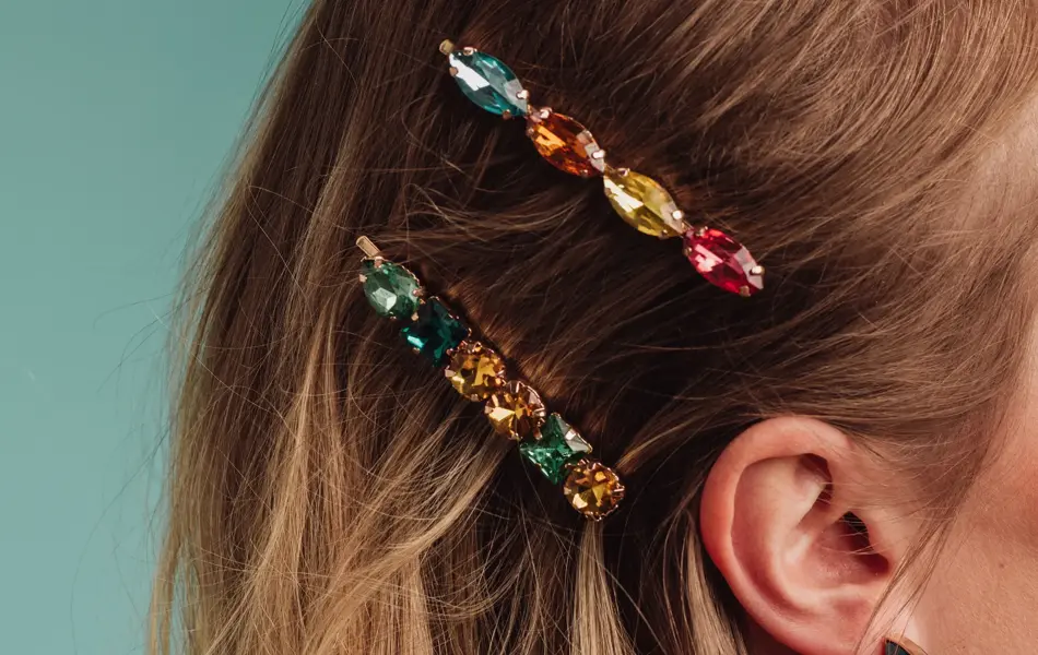 Nærbilde av to spenner med fargerike diamanter i håret på en kvinne
