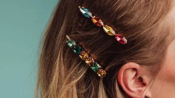 Nærbilde av to spenner med fargerike diamanter i håret på en kvinne