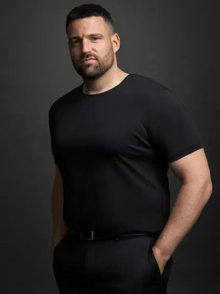 En mann i sort t-skjorte og bukser ser mot kamera