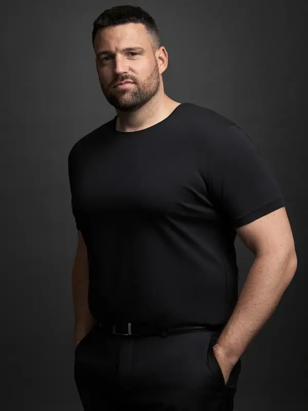 En mann i sort t-skjorte og bukser ser mot kamera