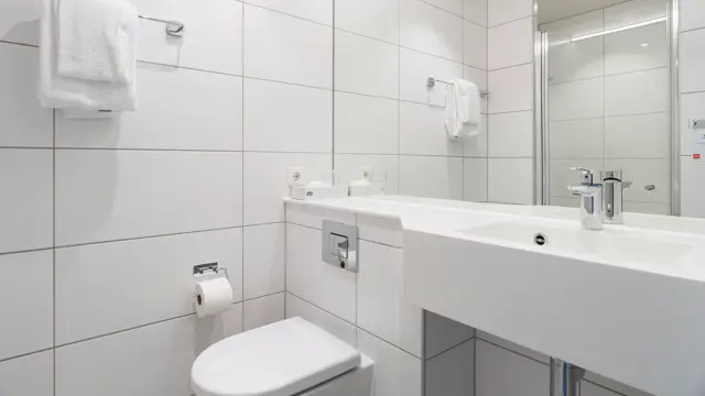 Flislagt bad med toalett og servant med speil over.