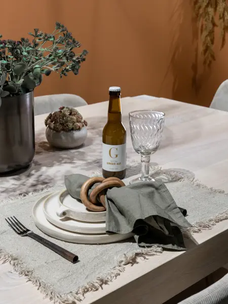 En dame som holder på med oppussing og tips om interiør trender for våren 2021. Damen har lyst halvlangt hå og har på seg en blå olaskjorte og blå olabukse. Fargene går i brunt og beige jordtoner og det er mye lilla og pastellfarger