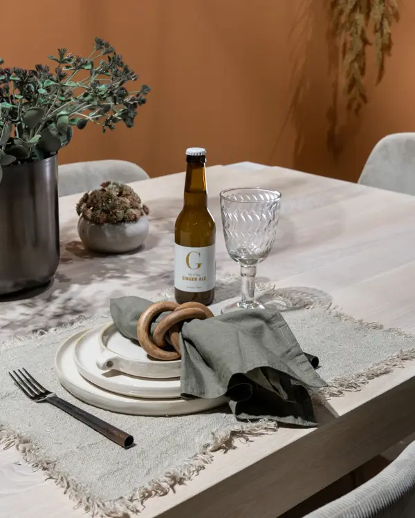 En dame som holder på med oppussing og tips om interiør trender for våren 2021. Damen har lyst halvlangt hå og har på seg en blå olaskjorte og blå olabukse. Fargene går i brunt og beige jordtoner og det er mye lilla og pastellfarger