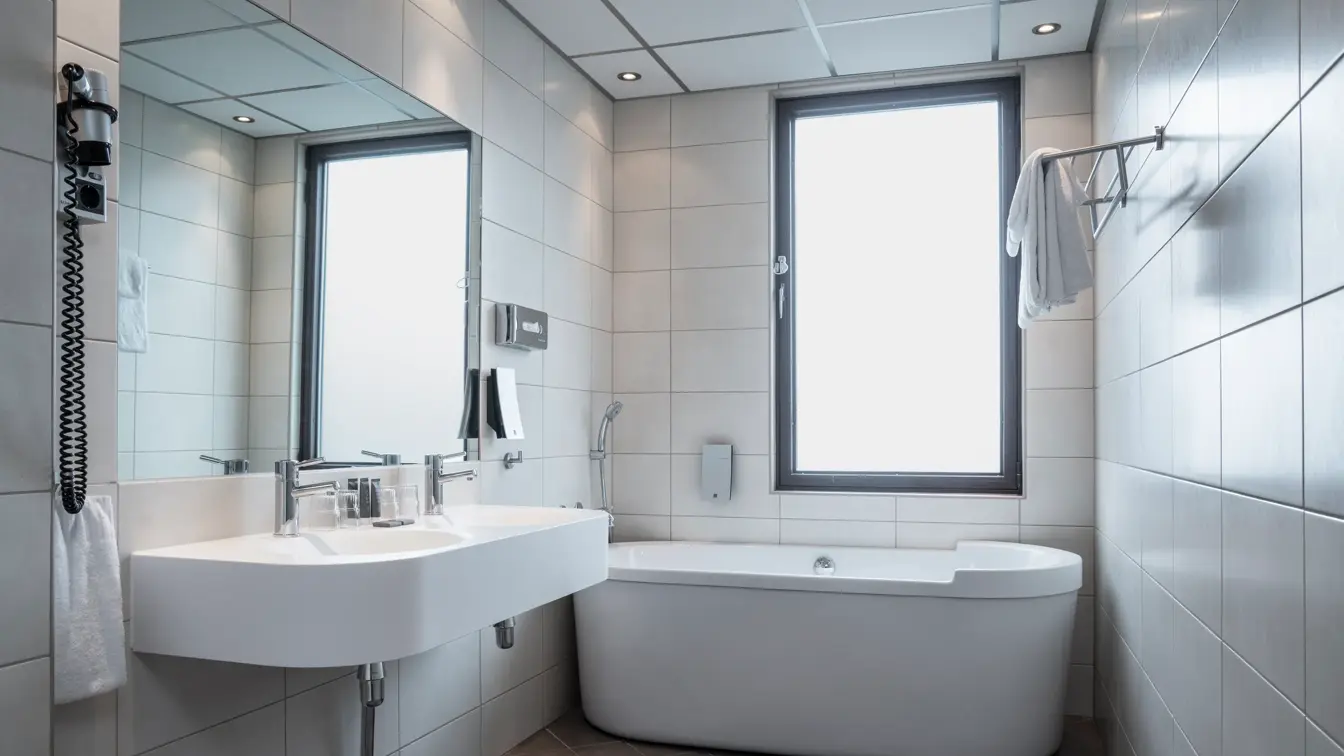 Badekar, vask, speil, hvite veggfliser, svarte gulvfliser