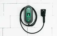 Ladekabel til el-bil henger på hvit vegg.