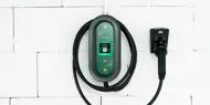 Ladekabel til el-bil henger på hvit vegg.