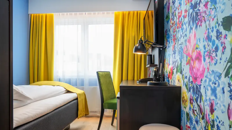 Seng, skrivebord,stol og blomstrete tapet på Thon Hotel Moldefjord
