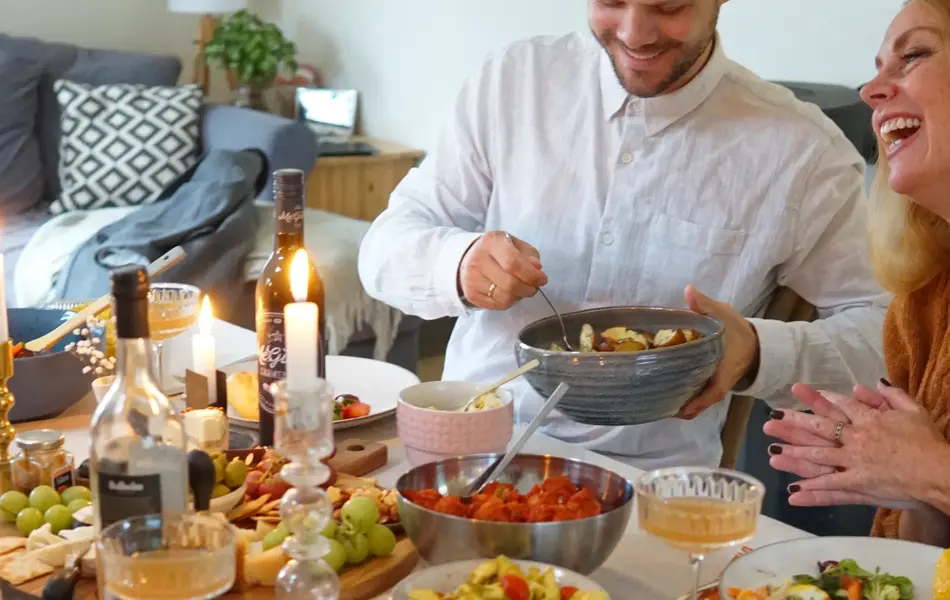 Dekket bord med mat og folk som smiler og deler mat