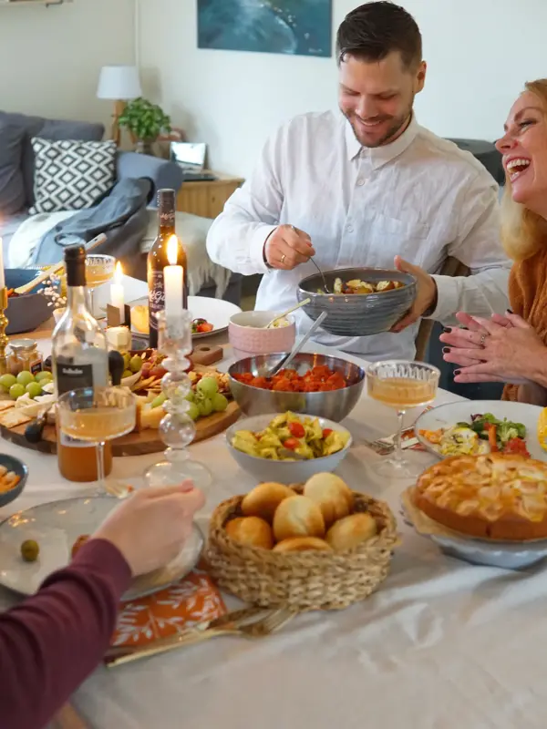 Dekket bord med mat og folk som smiler og deler mat