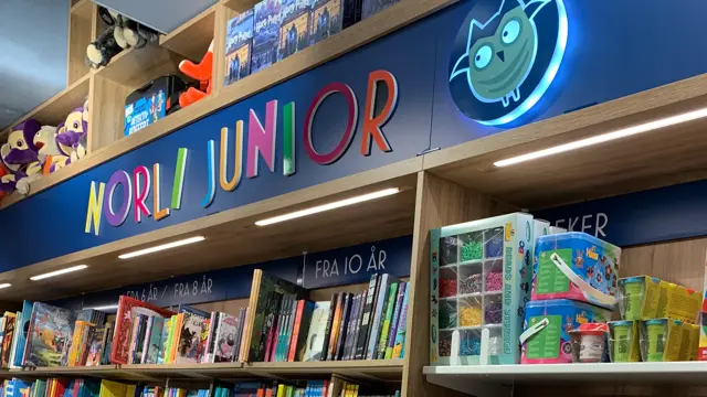 Norli med eikebokhyller fra gulv til tak fylt med bøker i ulike sjangre