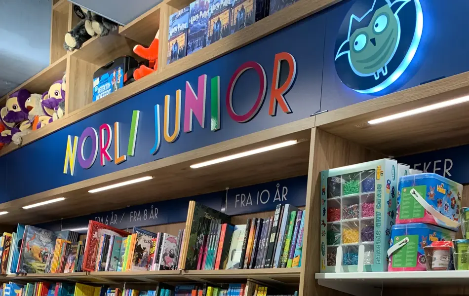 Norli med eikebokhyller fra gulv til tak fylt med bøker i ulike sjangre