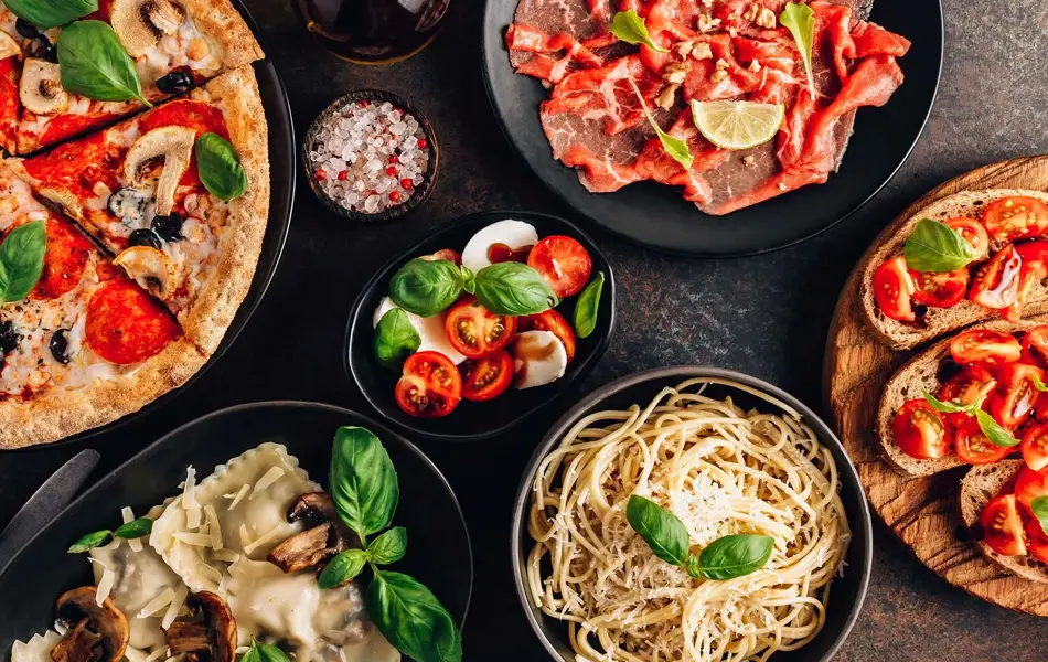 et bord med diverse italienske pasta retter, pizza og annet