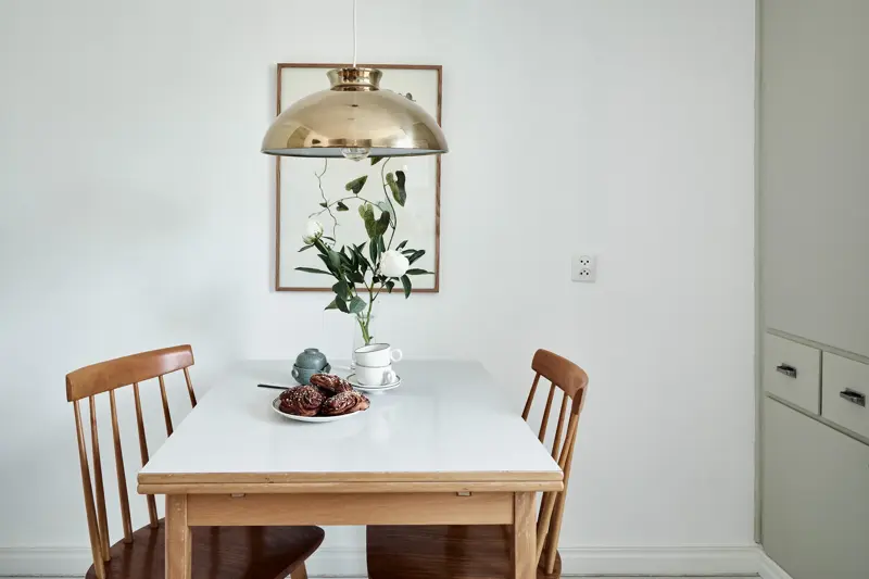 Spisebord med kanelboller på fat og sølvlampe hengende over