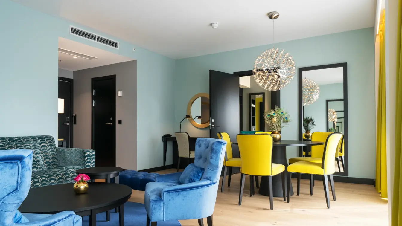 Spisebord med seks stoler og lyskrone. I tillegg er det sittegruppe med sofa på Thon Hotel Arendal i Arendal sentrum