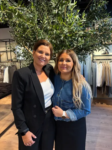 Dame med kort brunt hår og dame med langt lyst hår, kledd i sorte og hvite klær og ola klær