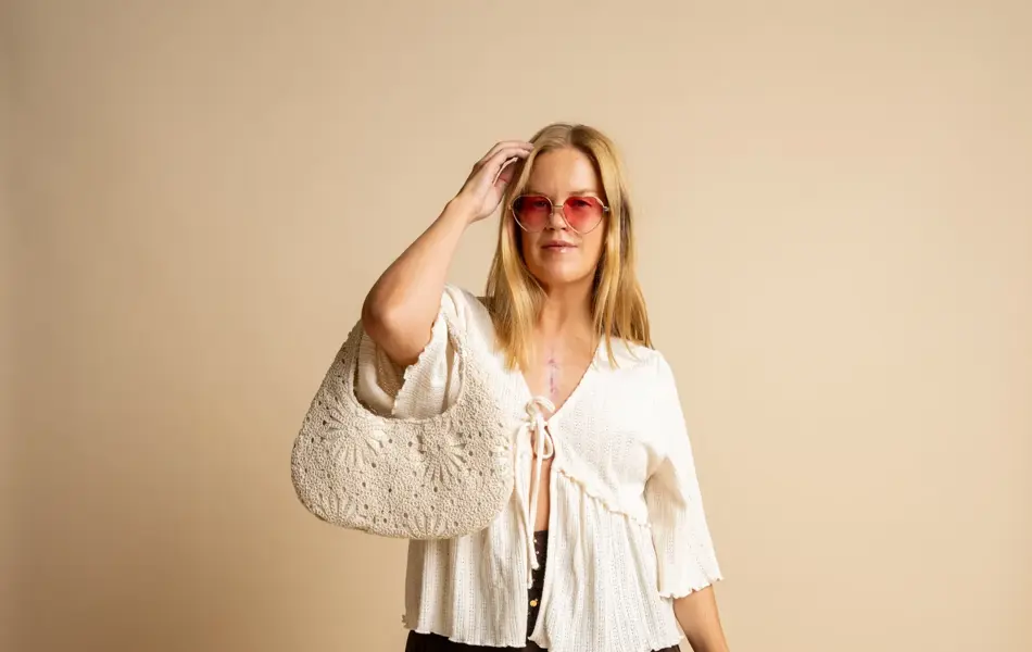 Damemodelle med rosa solbriller, hvit topp, brunt skjørt og hvit heklet veske.