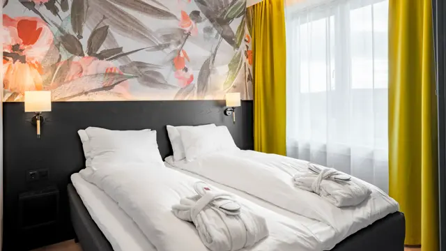 Junior suite med dobbeltseng, hvitt sengetøy, morgenkåpe og tøfler på sengen