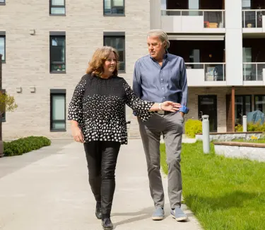 Bilde av Anne-Lise og Arild Amundsen som går utenfor blokken deres og peker på hagen
