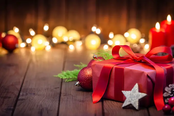 innpakket julegave på gulv med fine lys i bakgrunnen