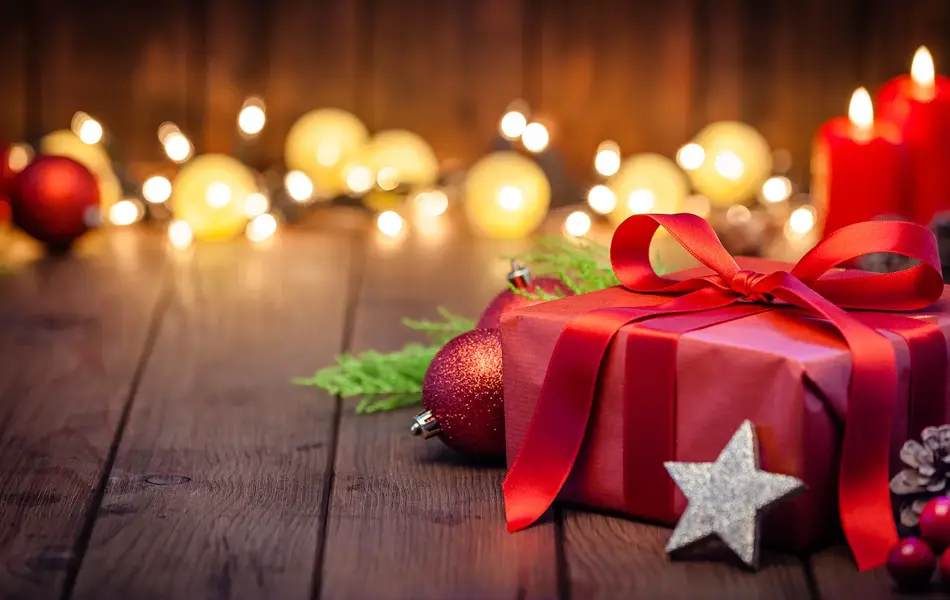innpakket julegave på gulv med fine lys i bakgrunnen