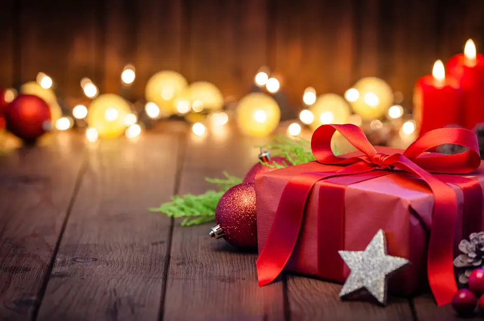 innpakket julegave på gulv med fine lys i bakgrunnen