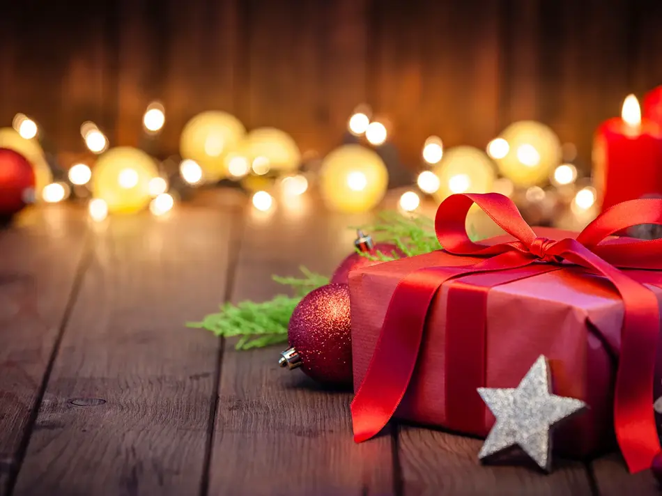 innpakket julegave på gulv med fine lys i bakgrunnen