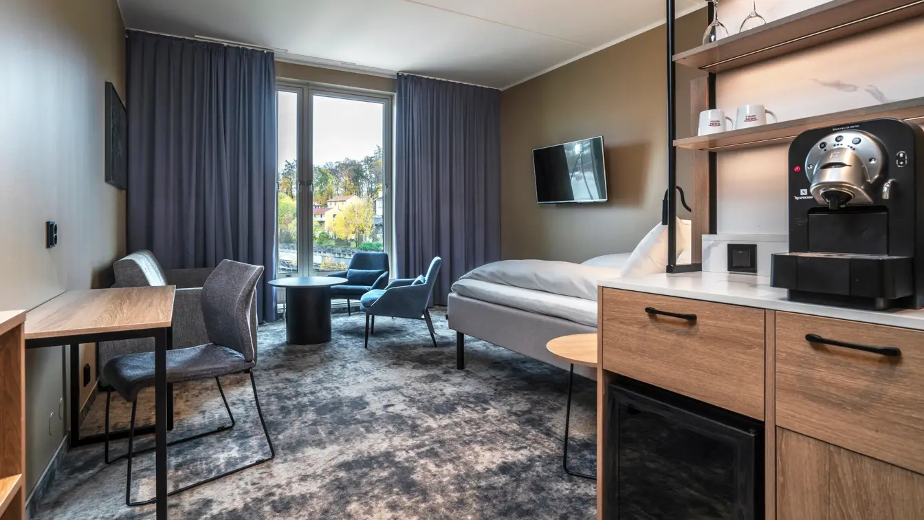 Businessrom med sittegruppe, skrivebord, Nespressomaskin, gardiner og gulvteppe