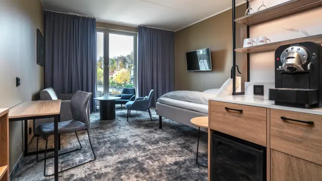 Businessrom med sittegruppe, skrivebord, Nespressomaskin, gardiner og gulvteppe