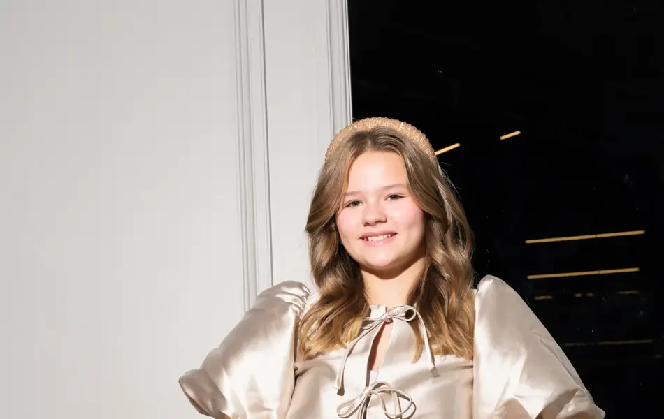 Jente i champagnefarget topp som smiler mot kamera