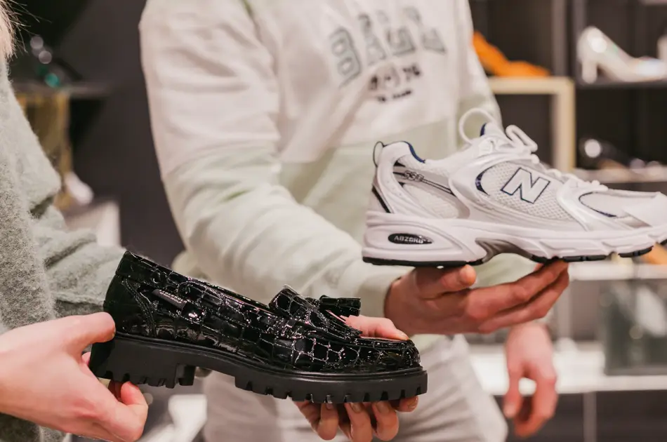 Mann og dame som står i butikk og viser frem sko