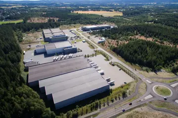 Dronebilde av stort lager- og logistikklokale, med rundkjøring og frodige omgivelser.