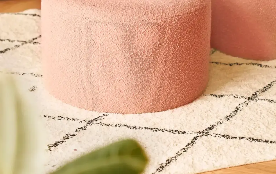 Interiørbilde i stue med ferskenfarget puff i sentrum.