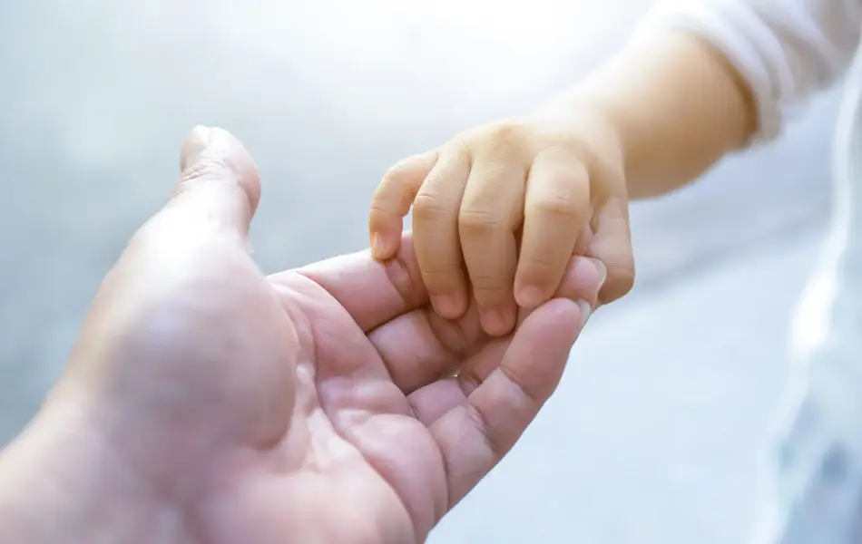 et barnehånd som holder i en voksen hånd