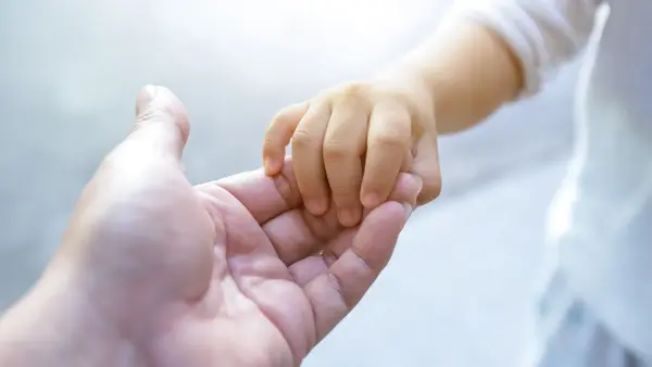 et barnehånd som holder i en voksen hånd