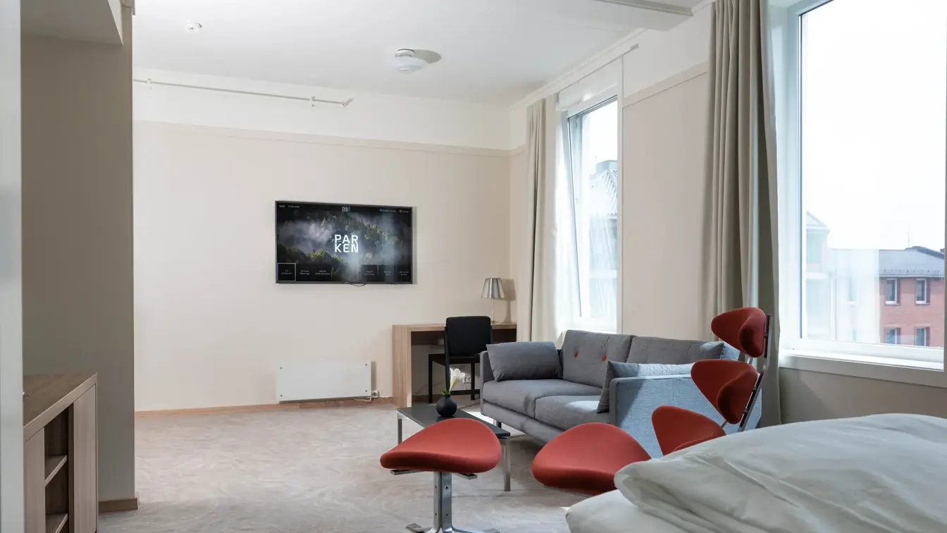 Bilde av sofa, bord og stol ved Tv-en i suiten